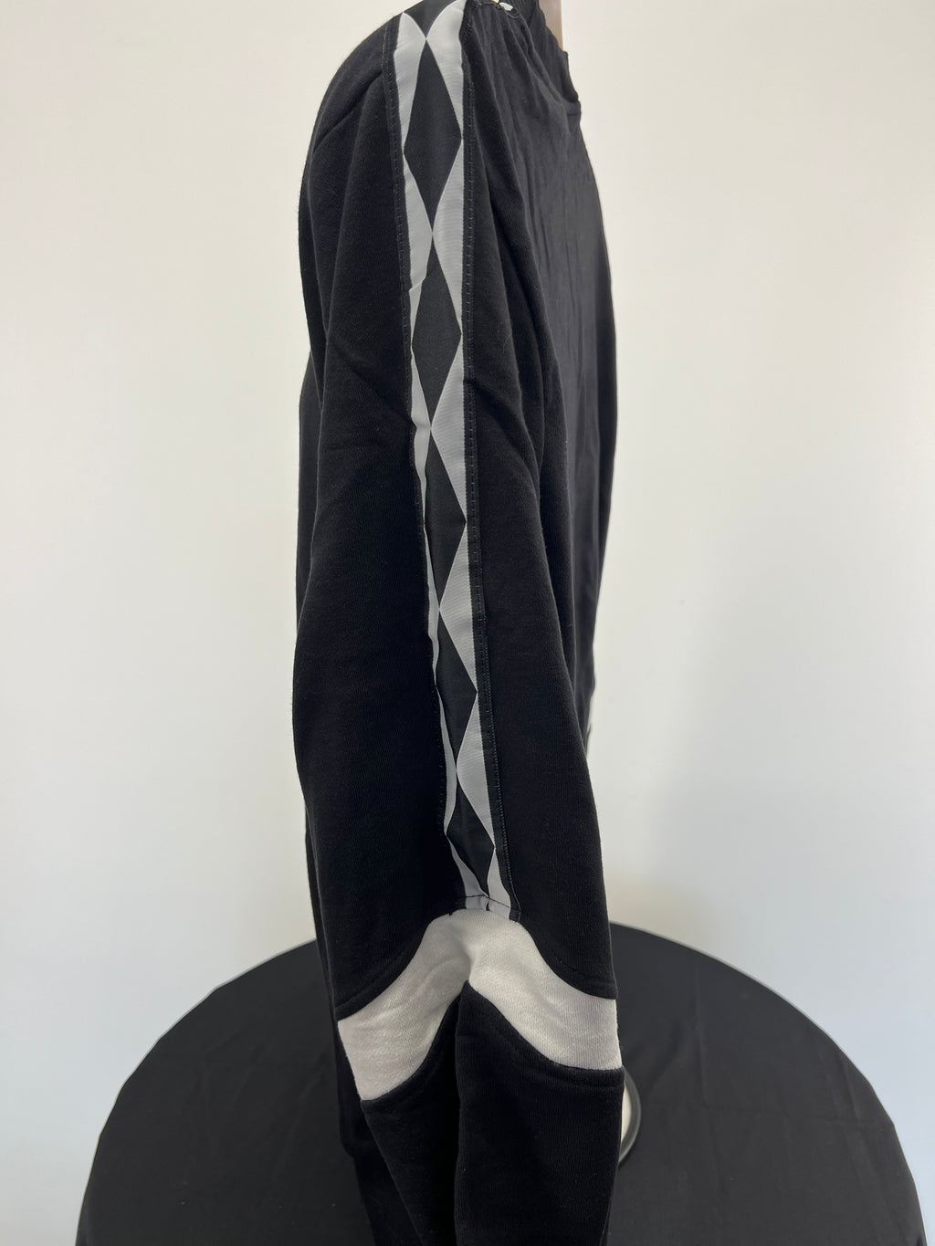 Side profile showing black sweatshirt sleeve with diamond patterned tape