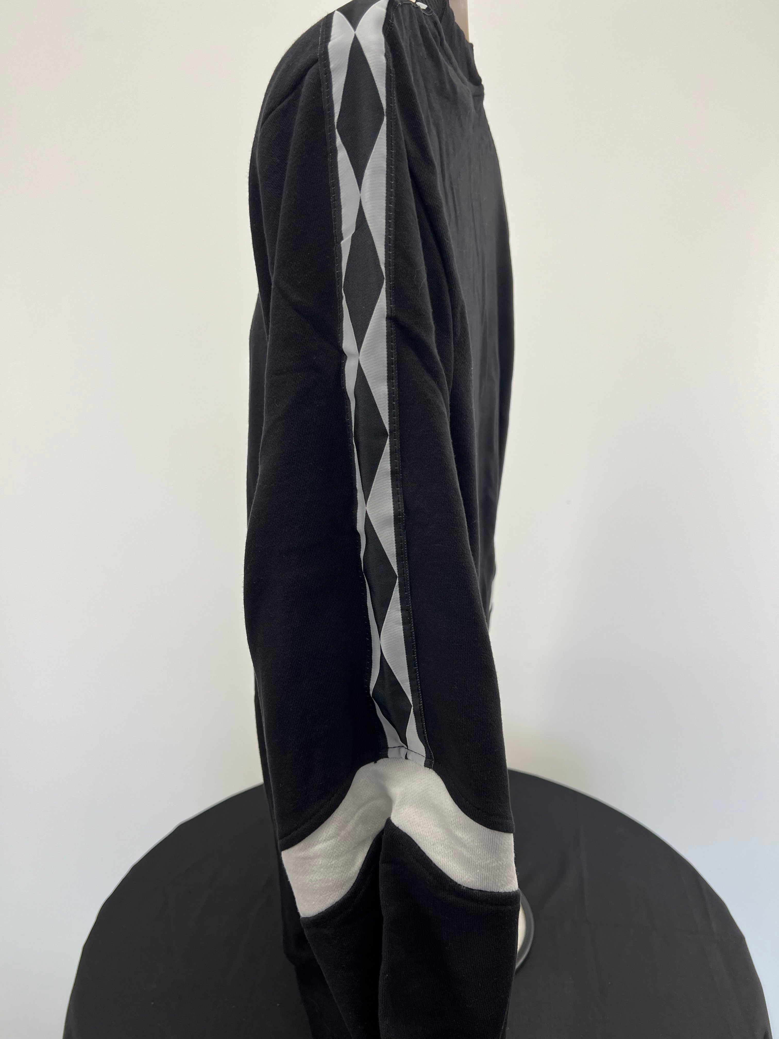 Side profile showing black sweatshirt sleeve with diamond patterned tape