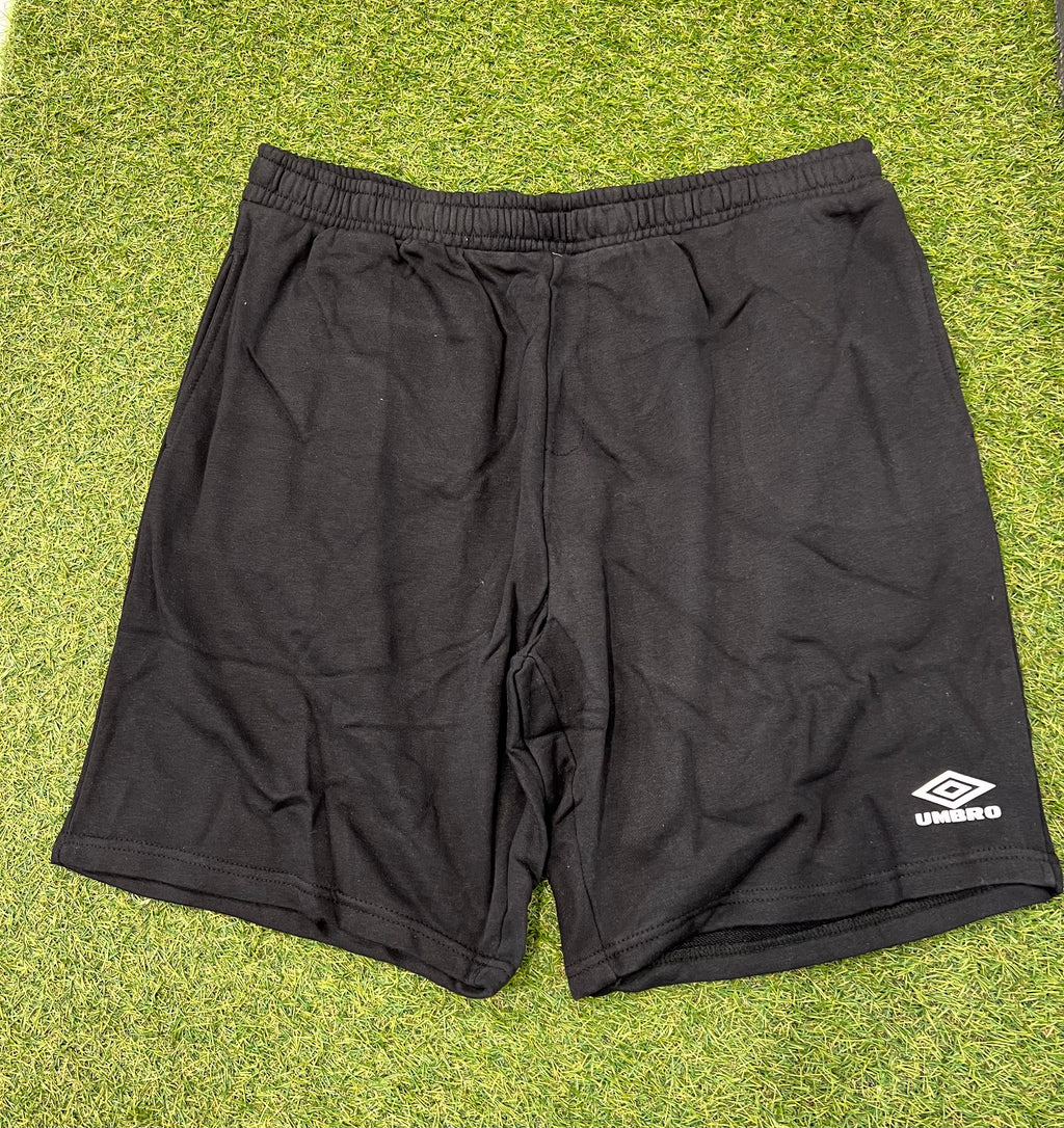 Front view of black Umbro Diamond Jog Shorts laid on grass showing elastic waistband and logo