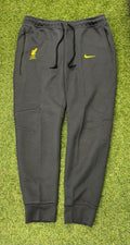 Front view of Nike Liverpool FC men's dark grey tracksuit trousers with yellow embroidered logos