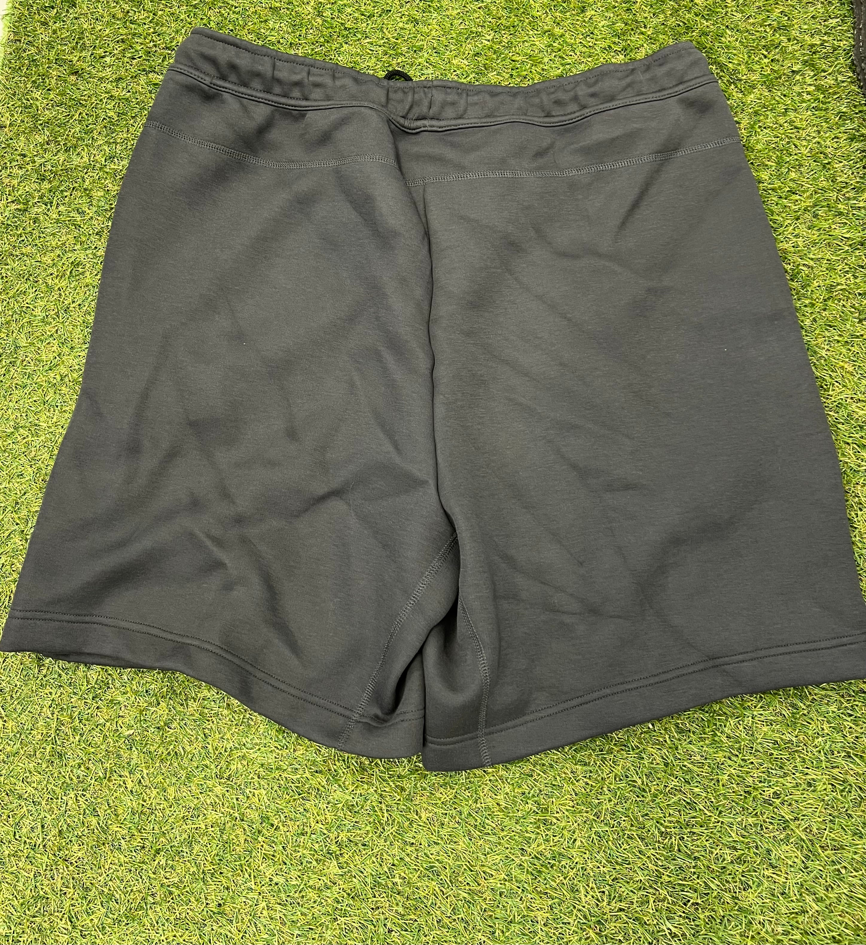Back view of plain black Nike men's shorts laid flat on grass