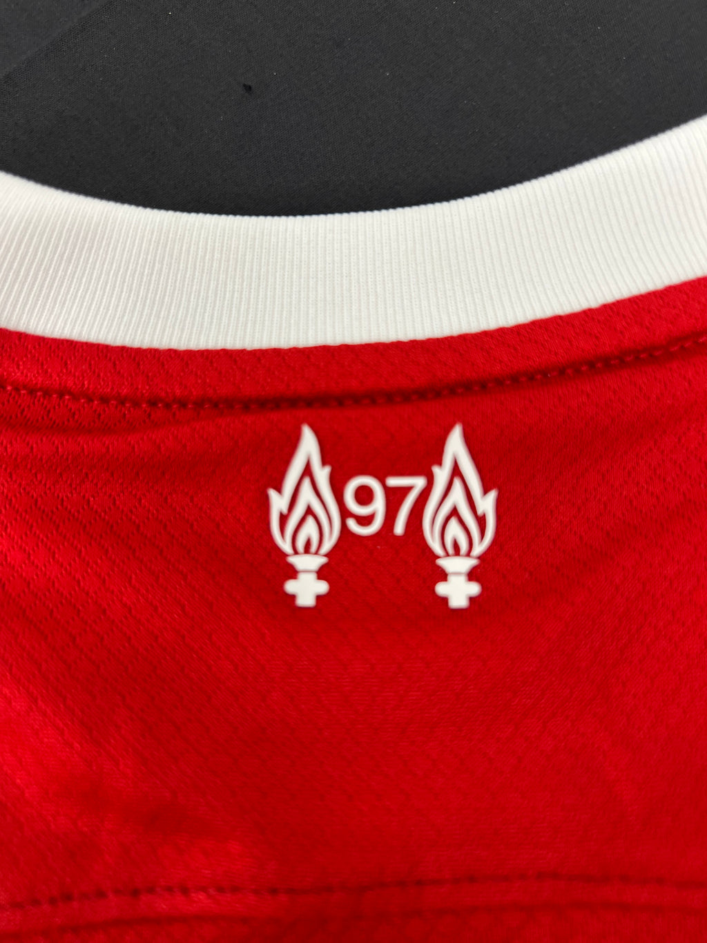 Close-up of back neckline detail with two flames and number 97 commemorative logo