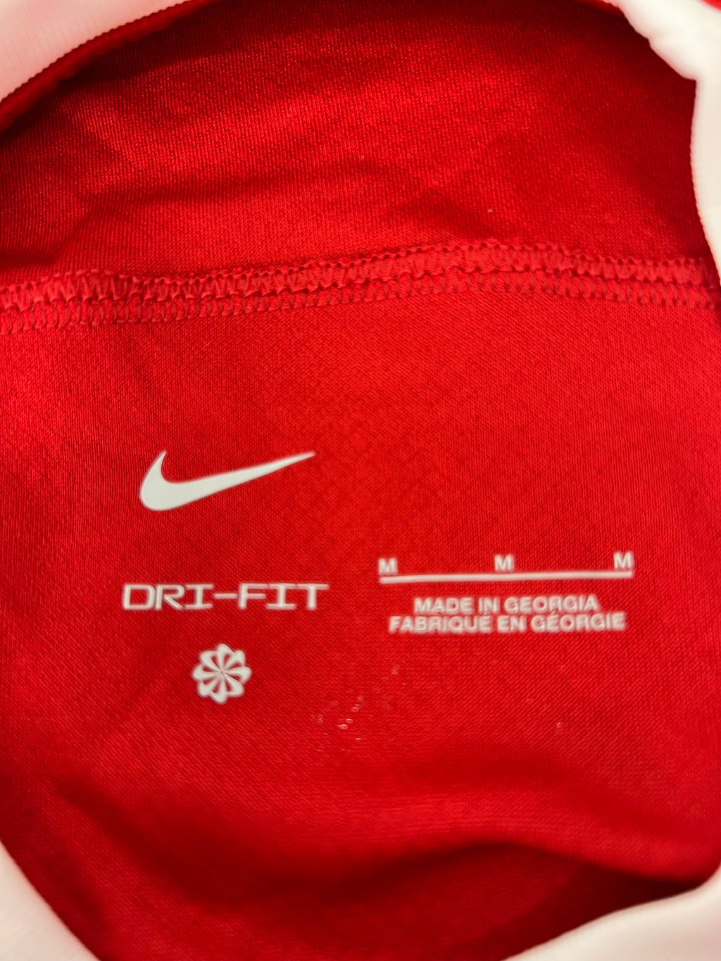 Inside label of Liverpool FC jersey showing Nike logo, size M, and made in Georgia