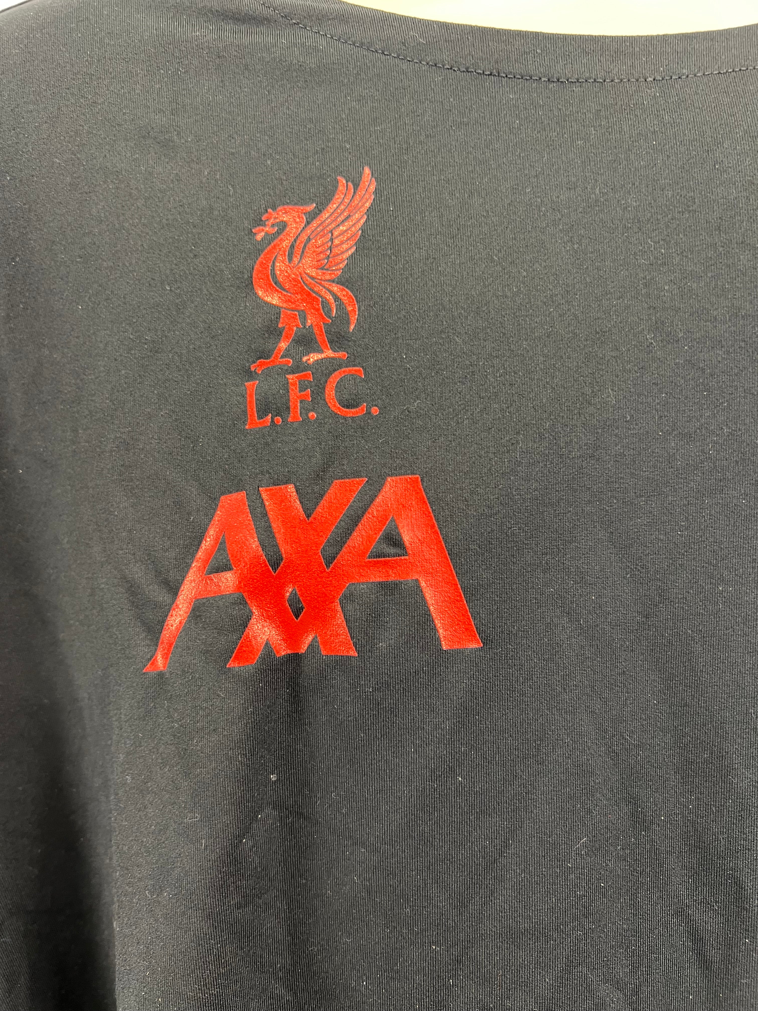 Close-up of red Liverpool FC and AXA logos on front of black Nike training top