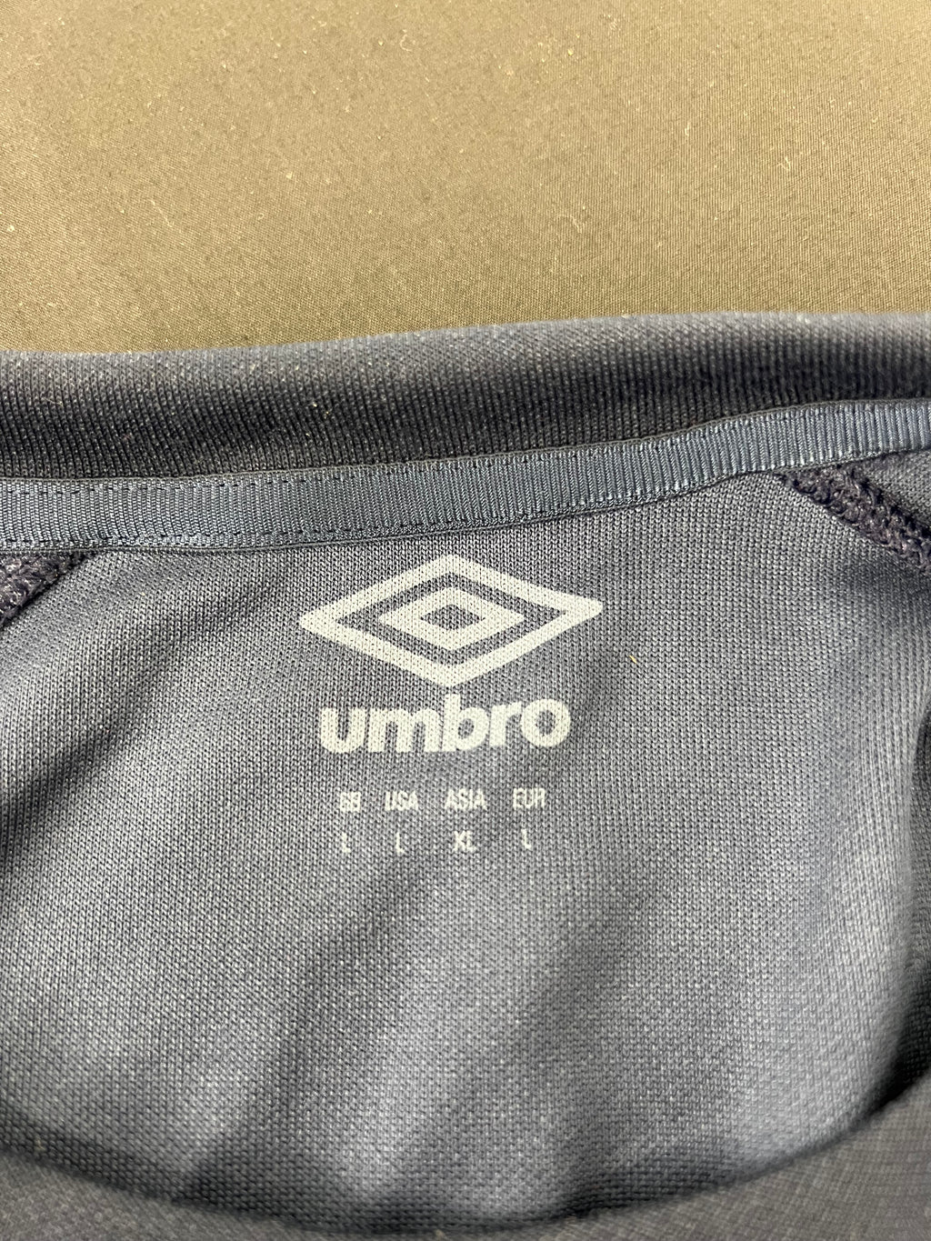 Close-up of Umbro logo and size label inside collar of navy rugby training top