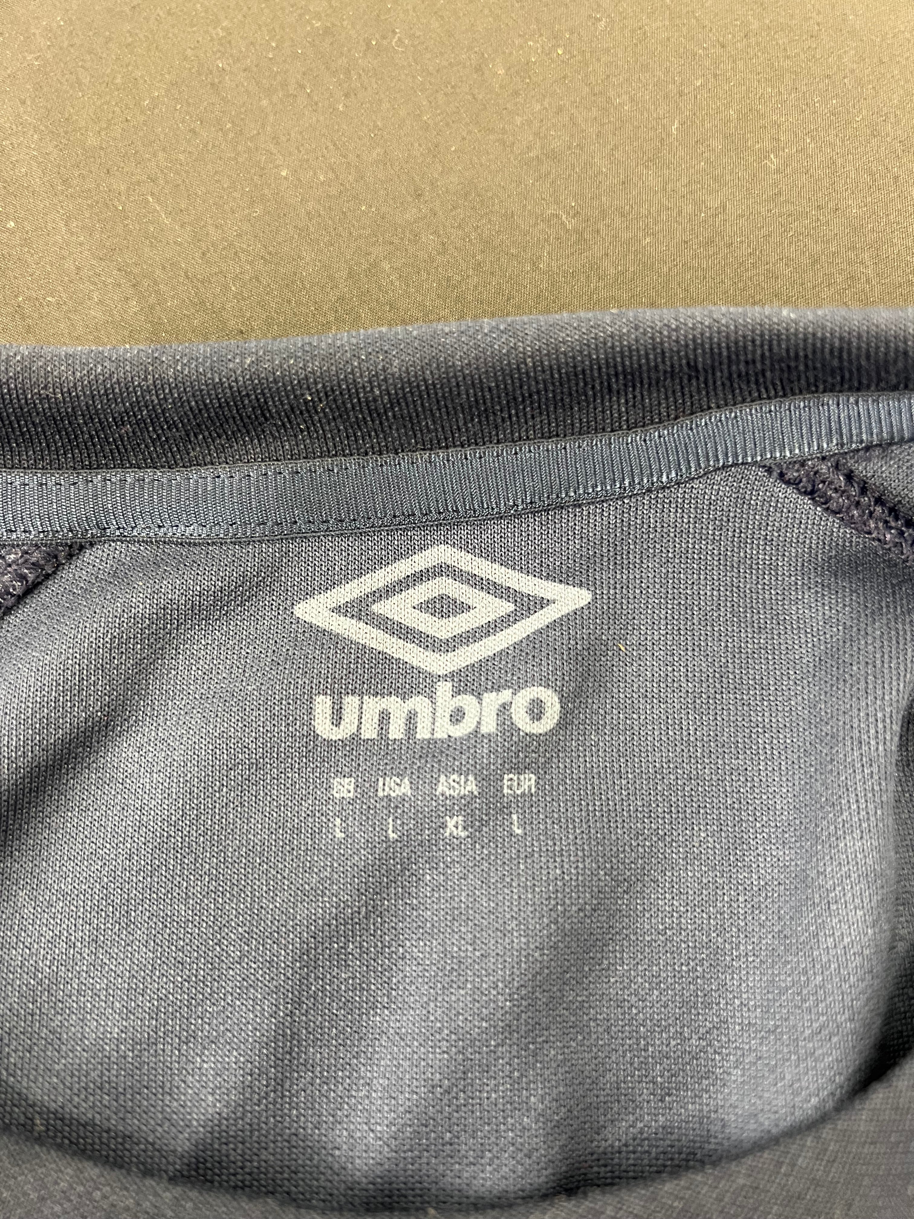 Close-up of Umbro logo and size label inside collar of navy rugby training top