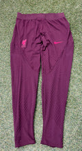 Full view of Liverpool FC Nike Dri-FIT ADV maroon training bottoms laid on grass