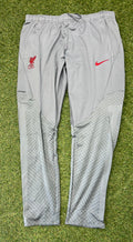 Front view of grey Nike Liverpool FC slim fit tracksuit bottoms laid flat on grass