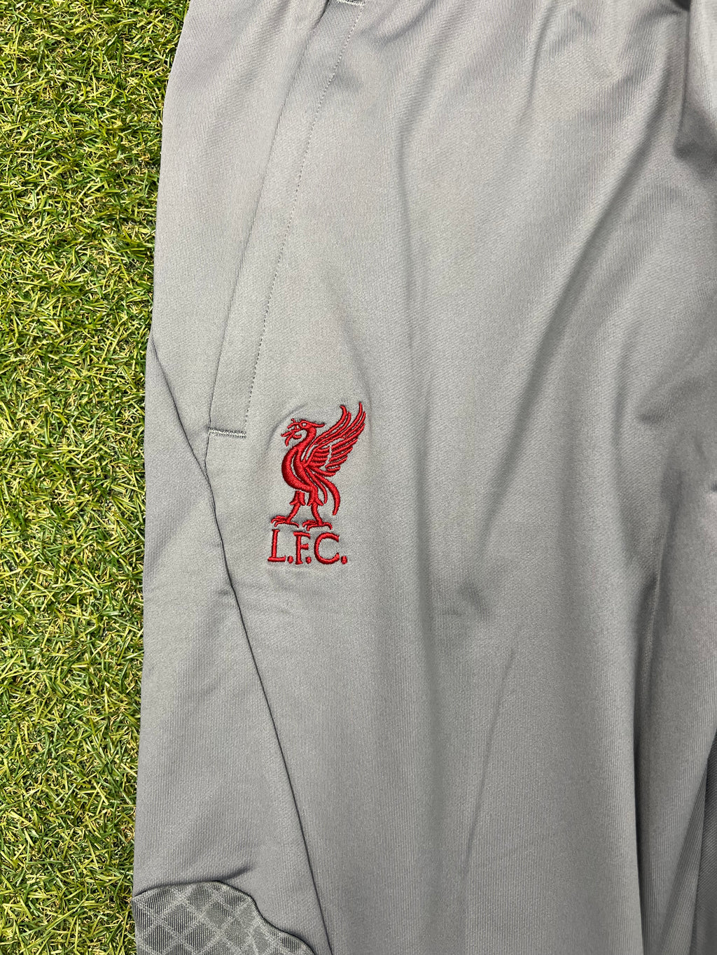 Close-up of Liverpool FC logo embroidered in red on grey fabric near pocket