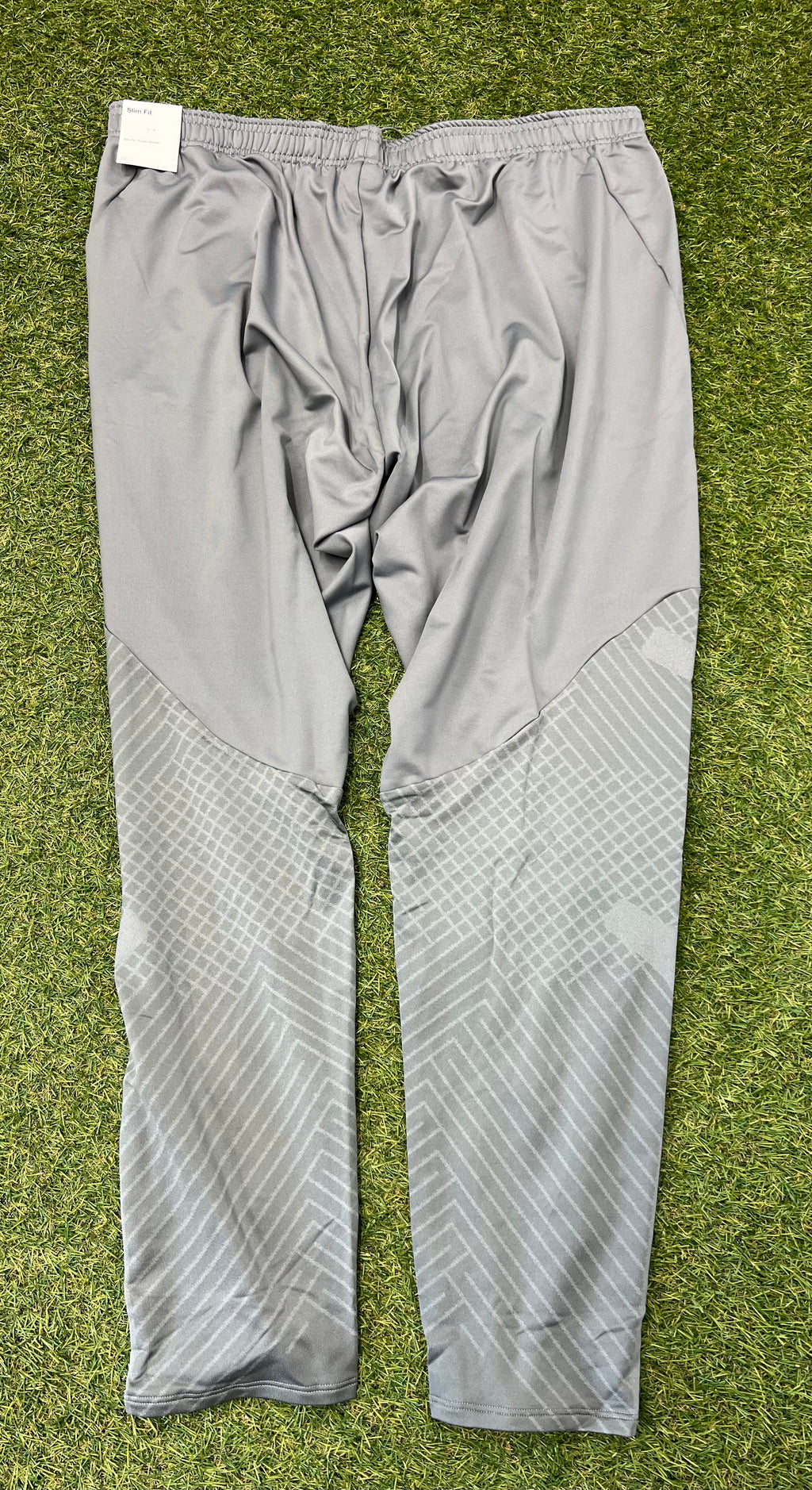 Rear view of grey slim fit tracksuit bottoms showing patterned lower leg panels