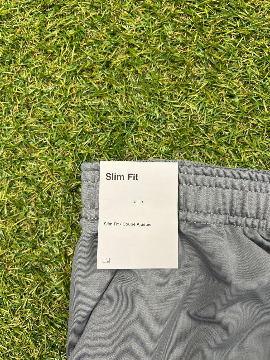 Tag showing 'Slim Fit' label attached to waistband of grey tracksuit bottoms