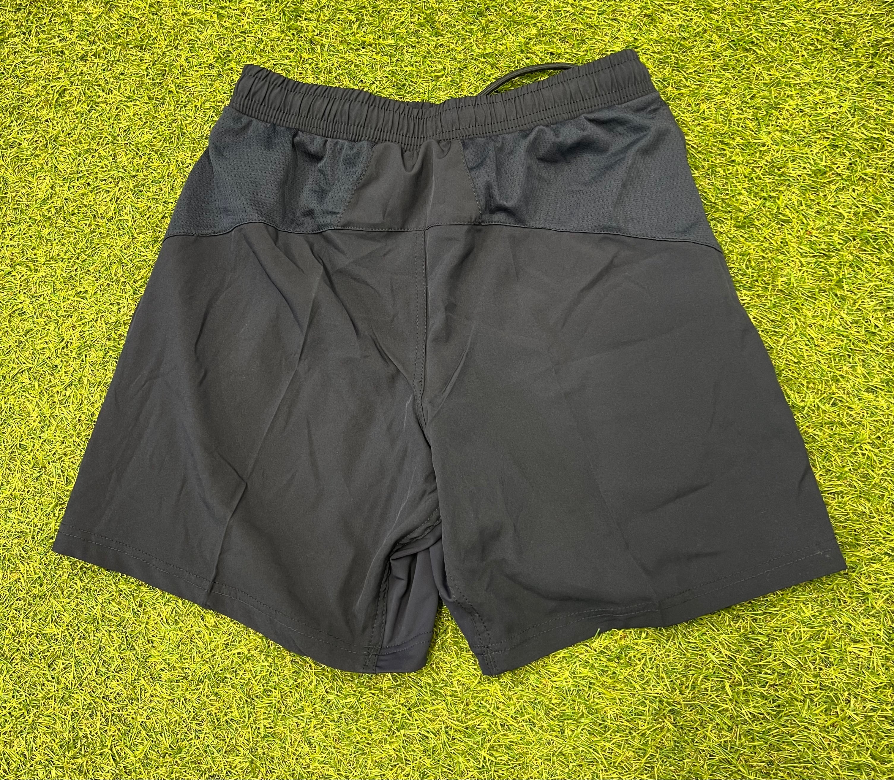 Back view of black BLK London Irish youth sports shorts showing mesh panels and elastic waistband.