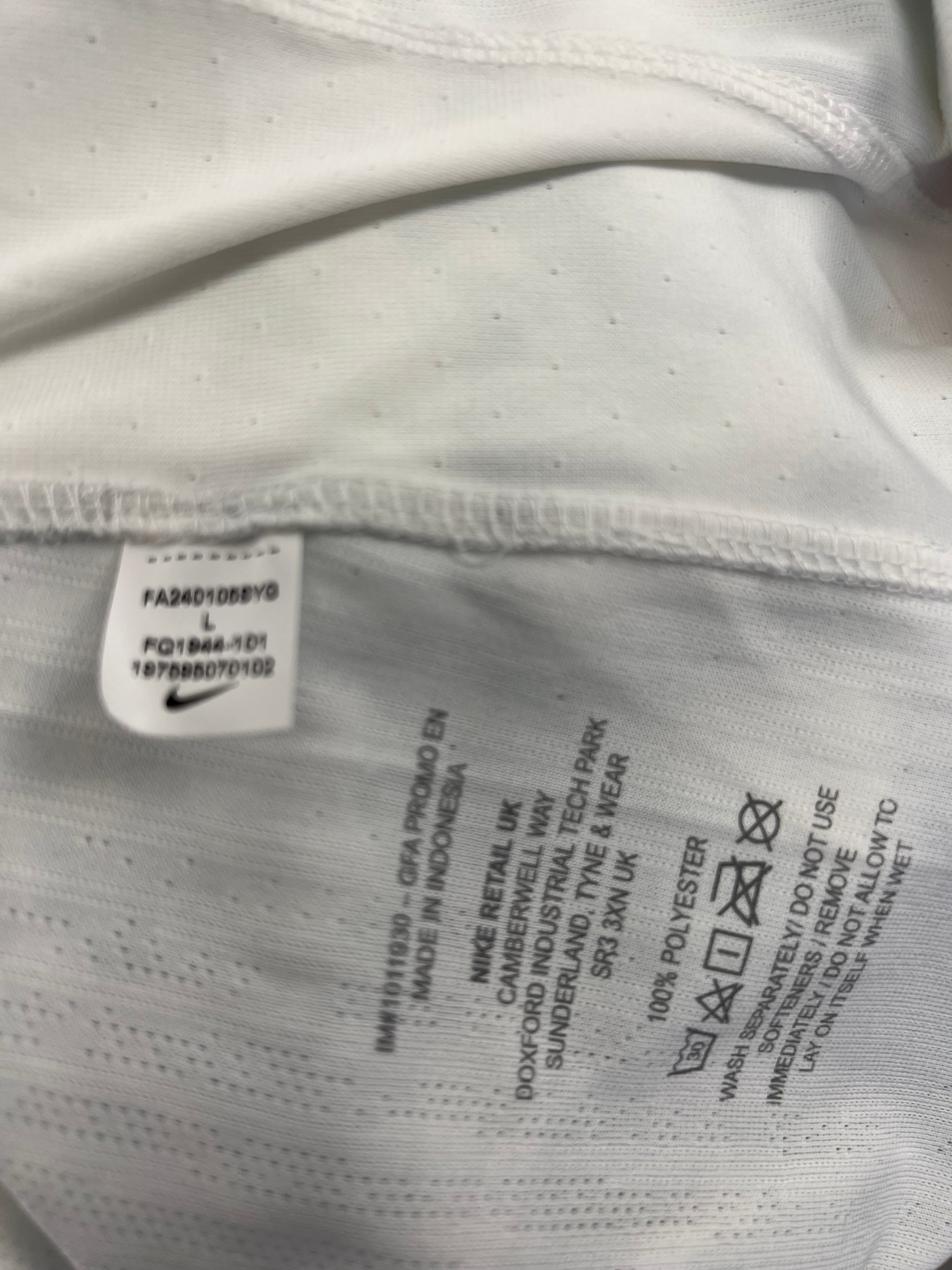 Close-up of Liverpool FC shirt care label showing 100% polyester material and washing instructions