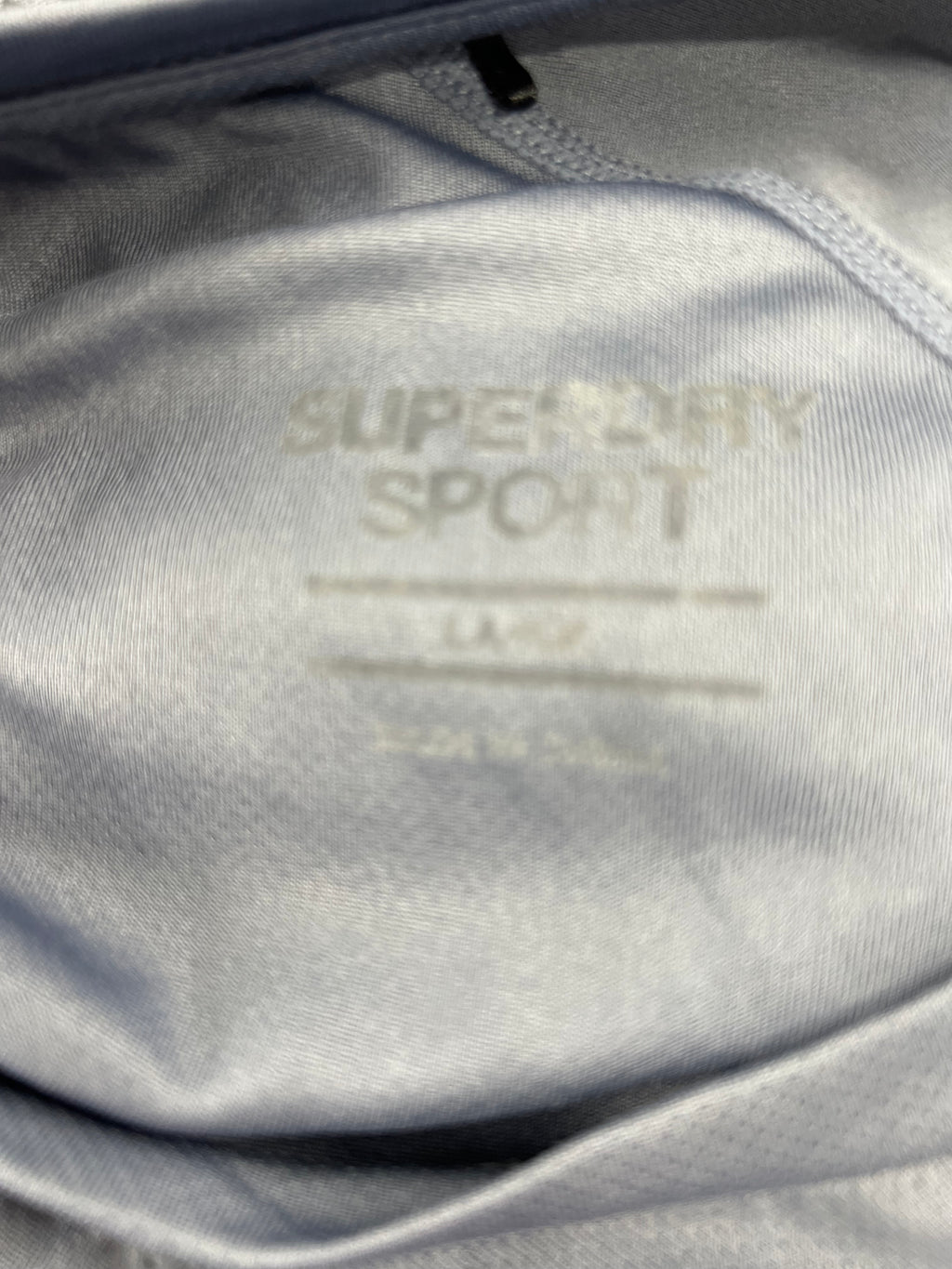 Close-up inside label of Superdry men's sports t-shirt showing size and brand