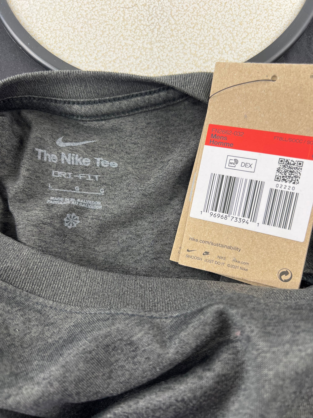 Close-up of neckline tag showing Nike 'The Nike Tee' branding and care instructions