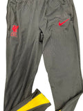 Black Liverpool FC training bottoms with red Nike swoosh and club crest on grass