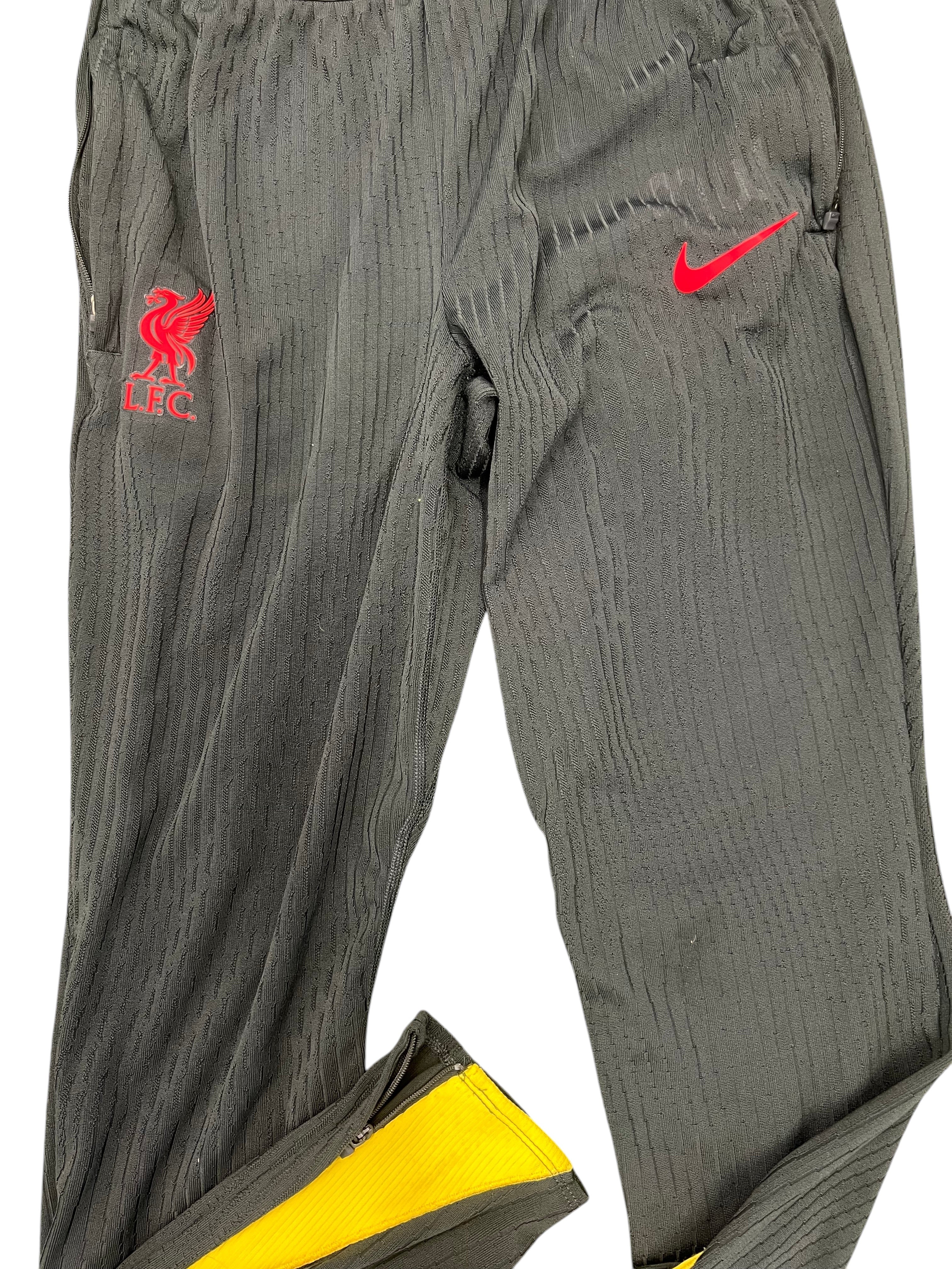 Black Liverpool FC training bottoms with red Nike swoosh and club crest on grass