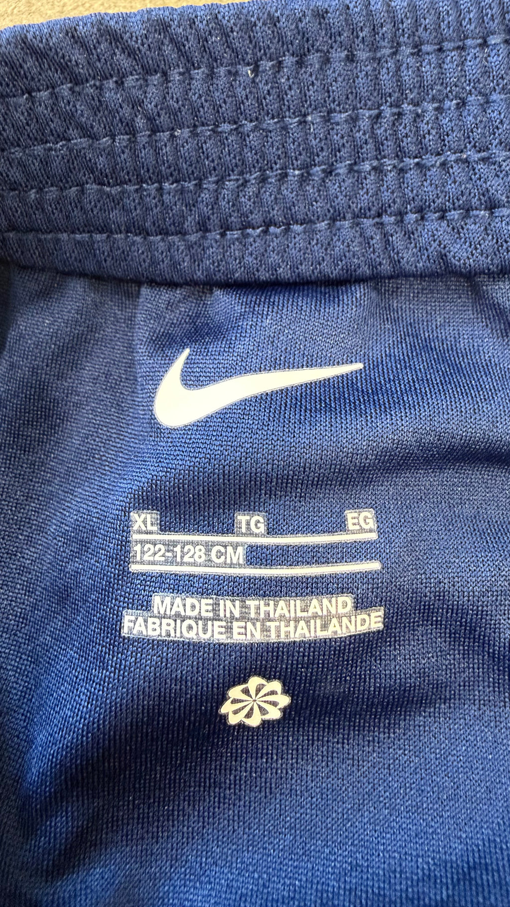 Close-up of inside shorts label showing Nike logo, XL size 122-128cm, and origin
