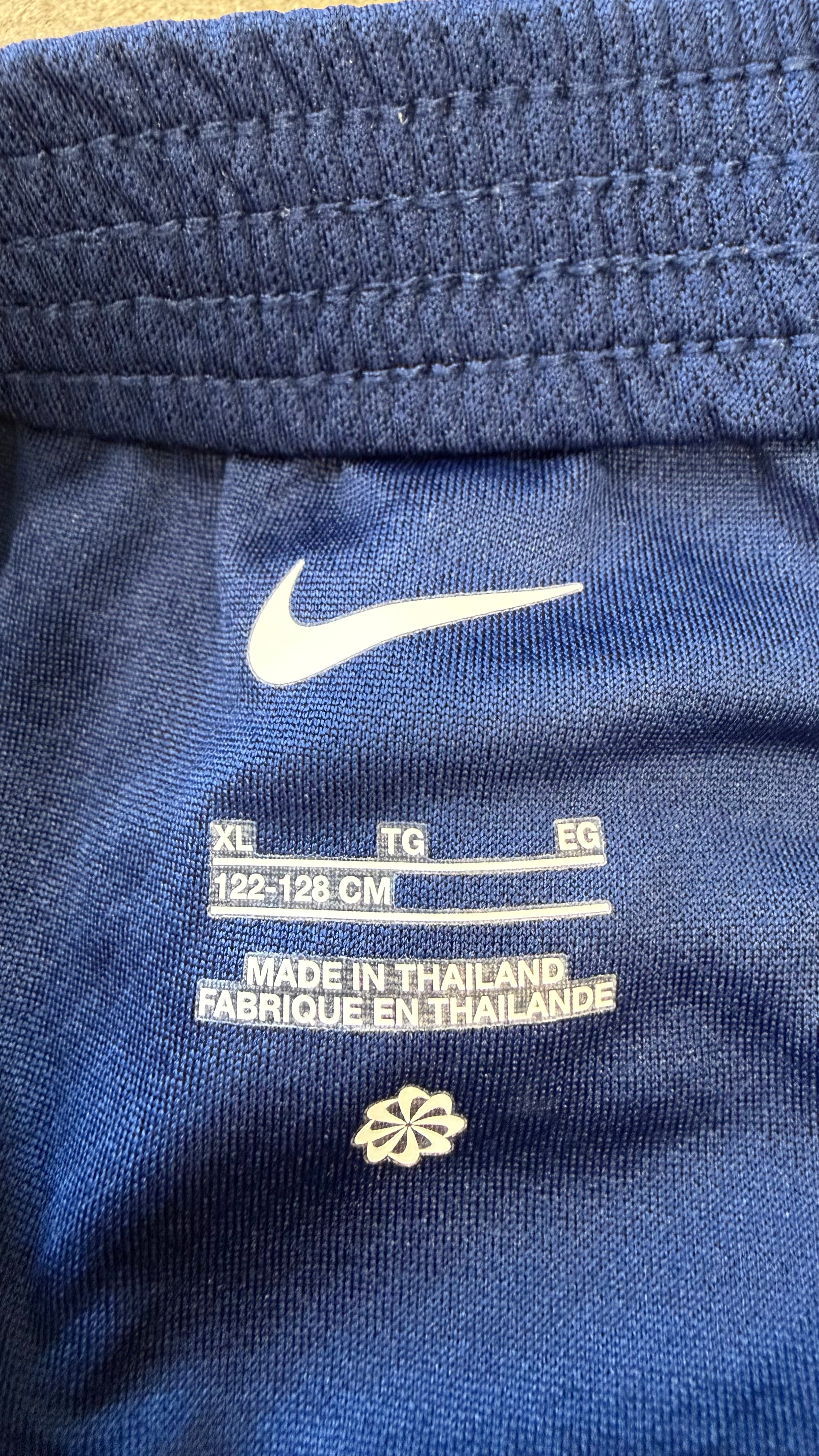 Close-up of inside shorts label showing Nike logo, XL size 122-128cm, and origin