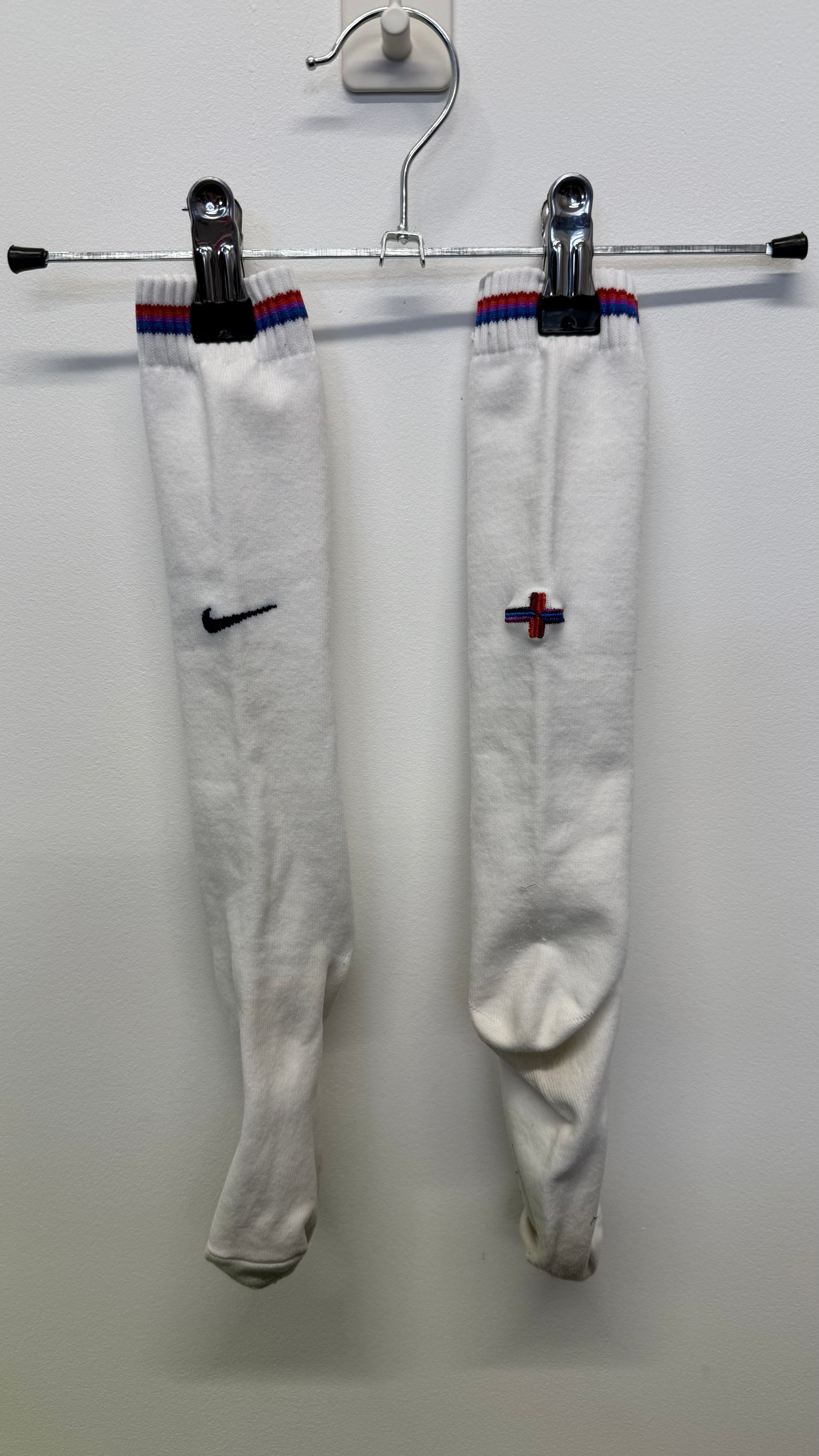 Pair of white Nike football socks with blue and red stripes