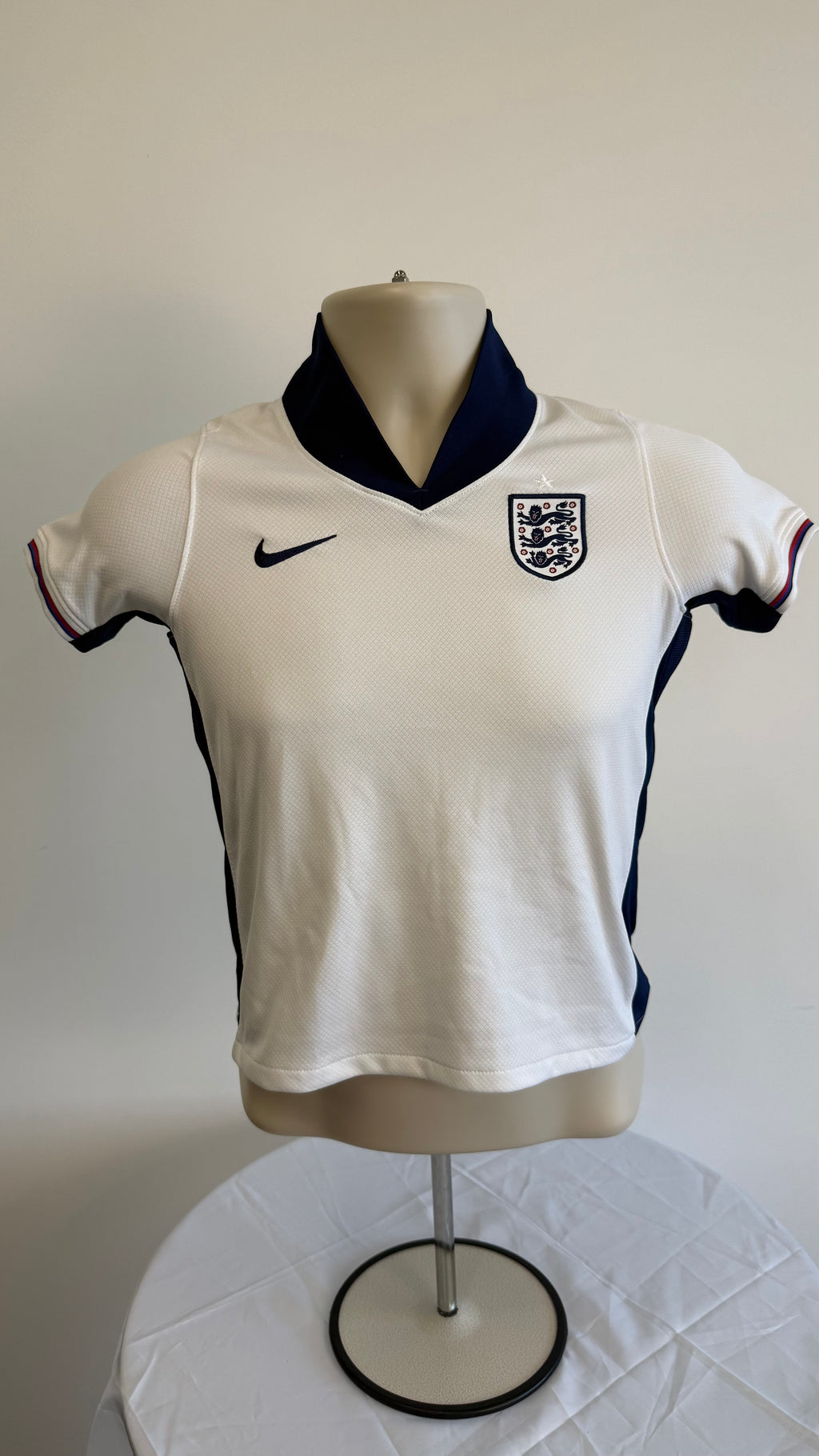 Front of kids England Nike football shirt with navy collar and England crest
