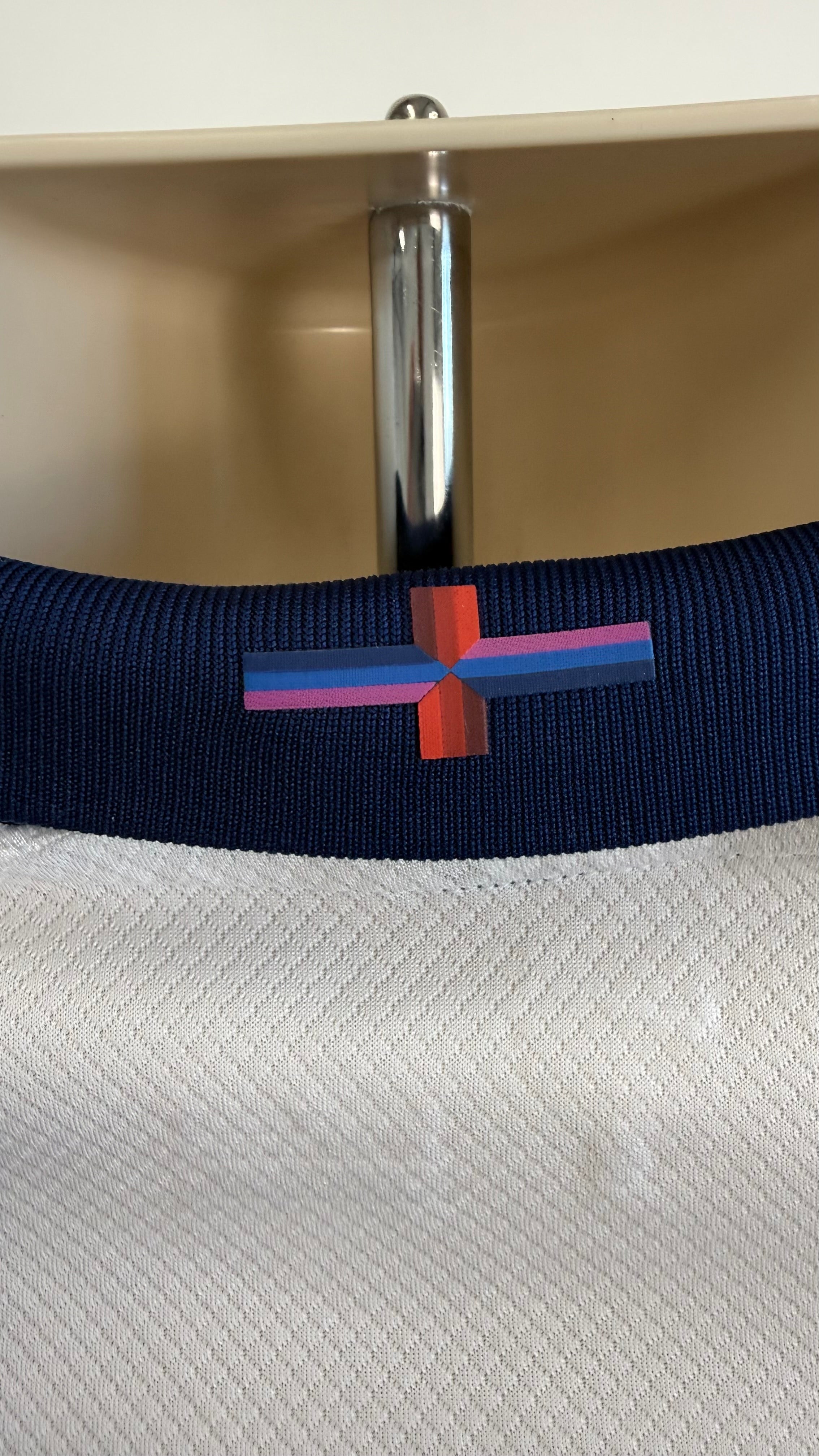 Close-up of England cross logo on navy shirt collar