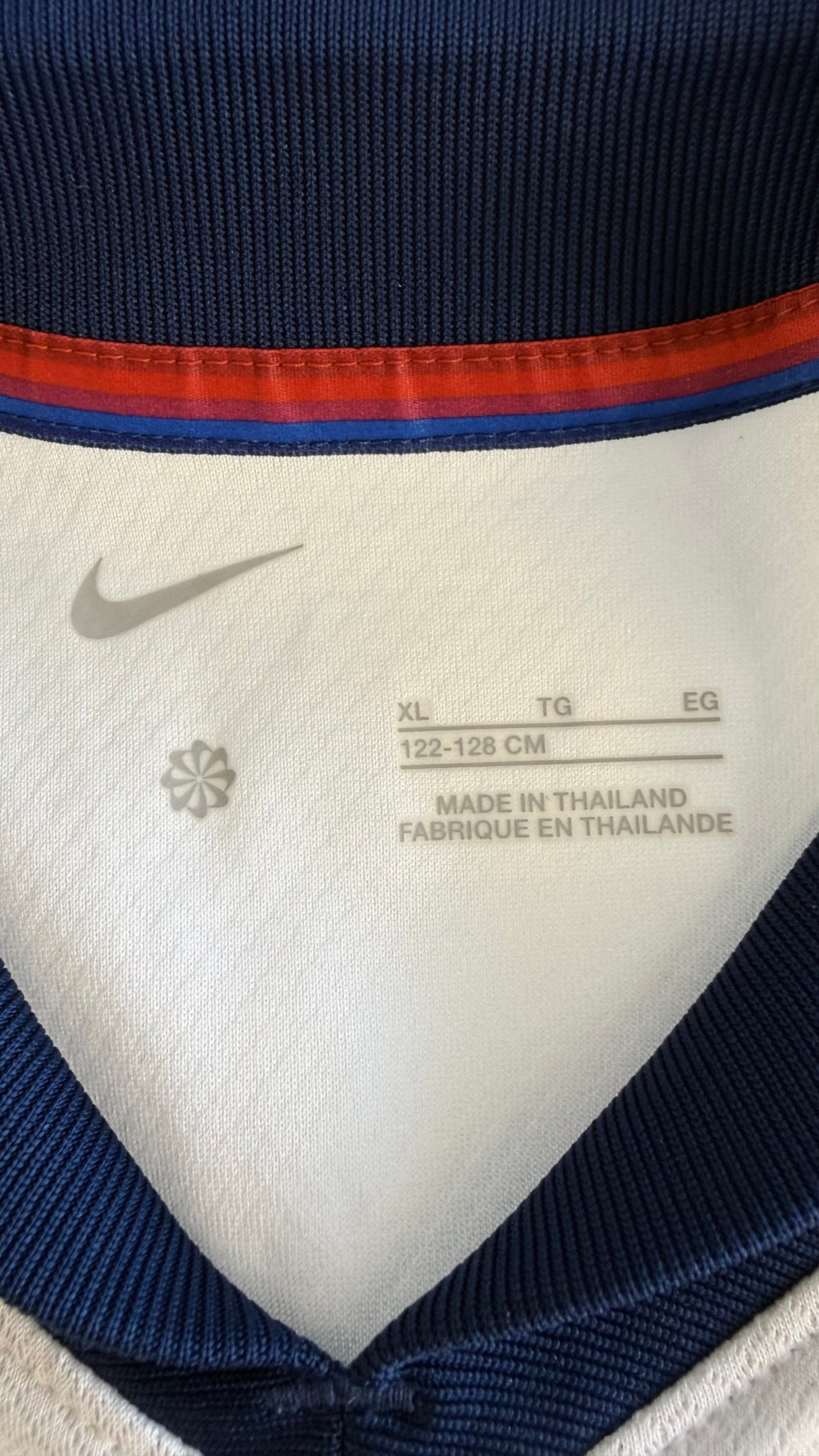 Close-up of inside shirt label showing Nike logo, XL size 122-128cm, and origin