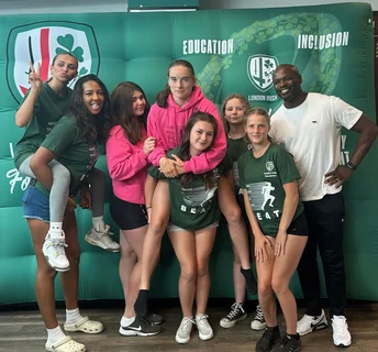Group of people posing in front of a green banner with logos and text.