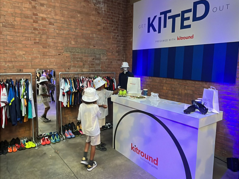 People shopping for clothes in a store with 'Kitted Out' and 'Kitround' branding.