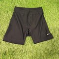 Front view of black Nike women's athletic shorts laid flat on grass background