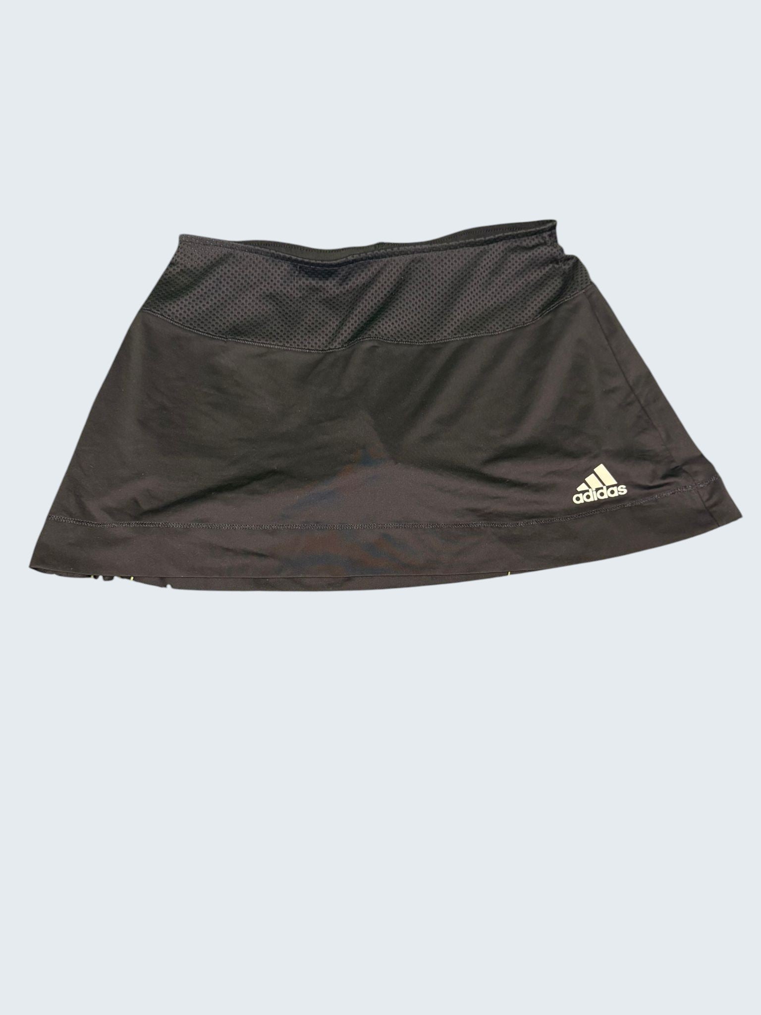 Front view of black Adidas tennis skirt with mesh waistband laid flat on grass