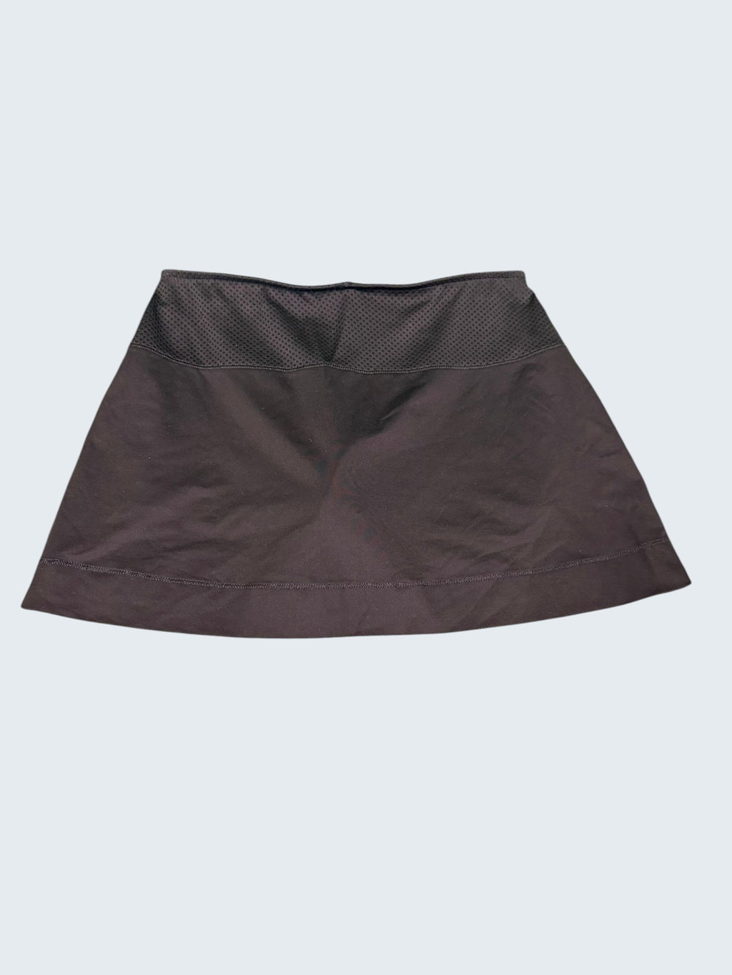 Back view of black Adidas tennis skirt with mesh waistband laid flat on grass