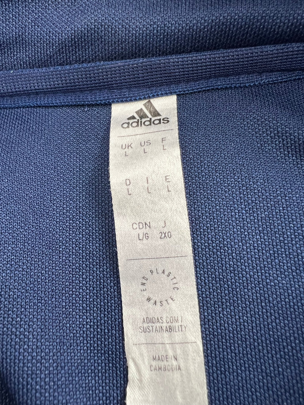Close-up of adidas clothing label showing size and sustainability information