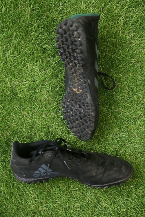 Side view of black adidas astro turf football boots showing adidas branding and studded sole