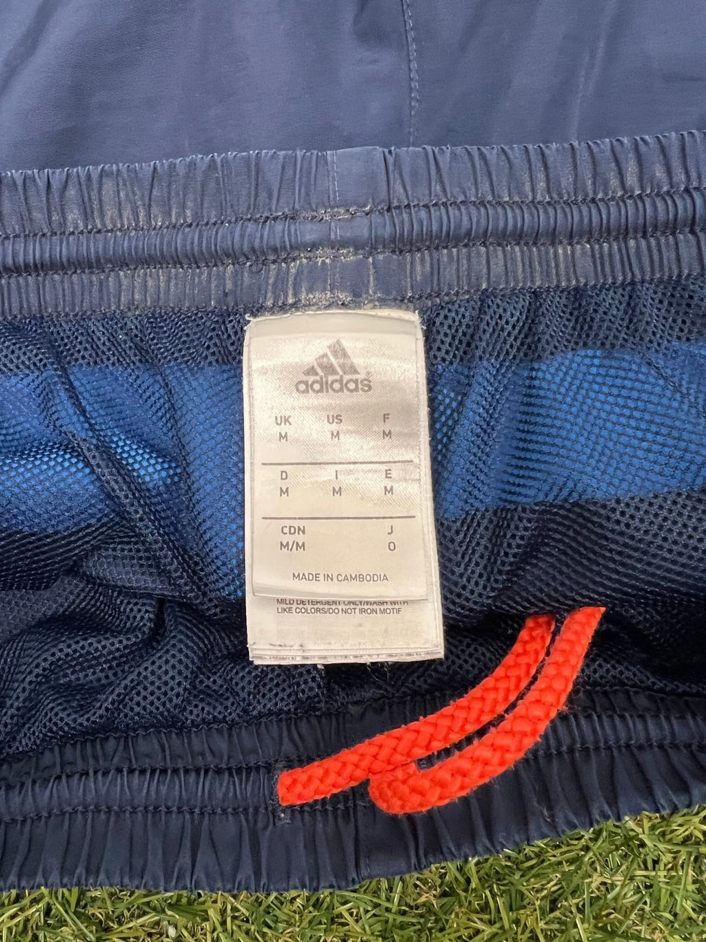 Close-up of adidas shorts label and orange drawstring