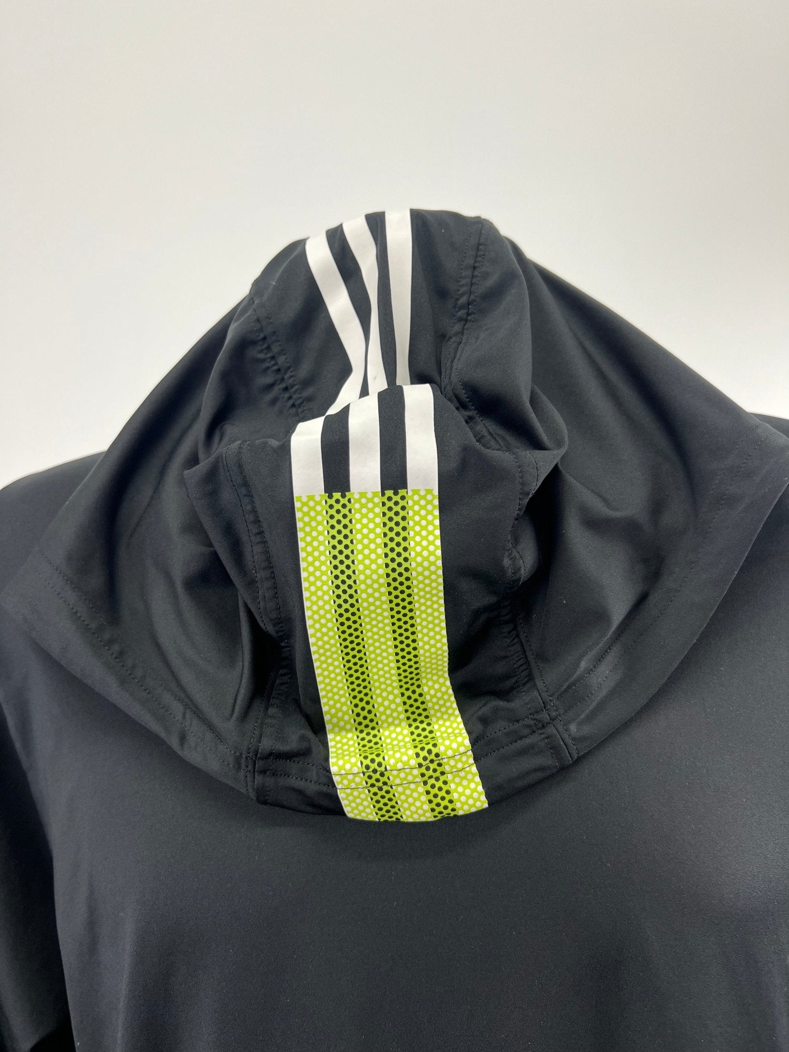 Close-up of hood with white and yellow adidas stripes on black Freelift top