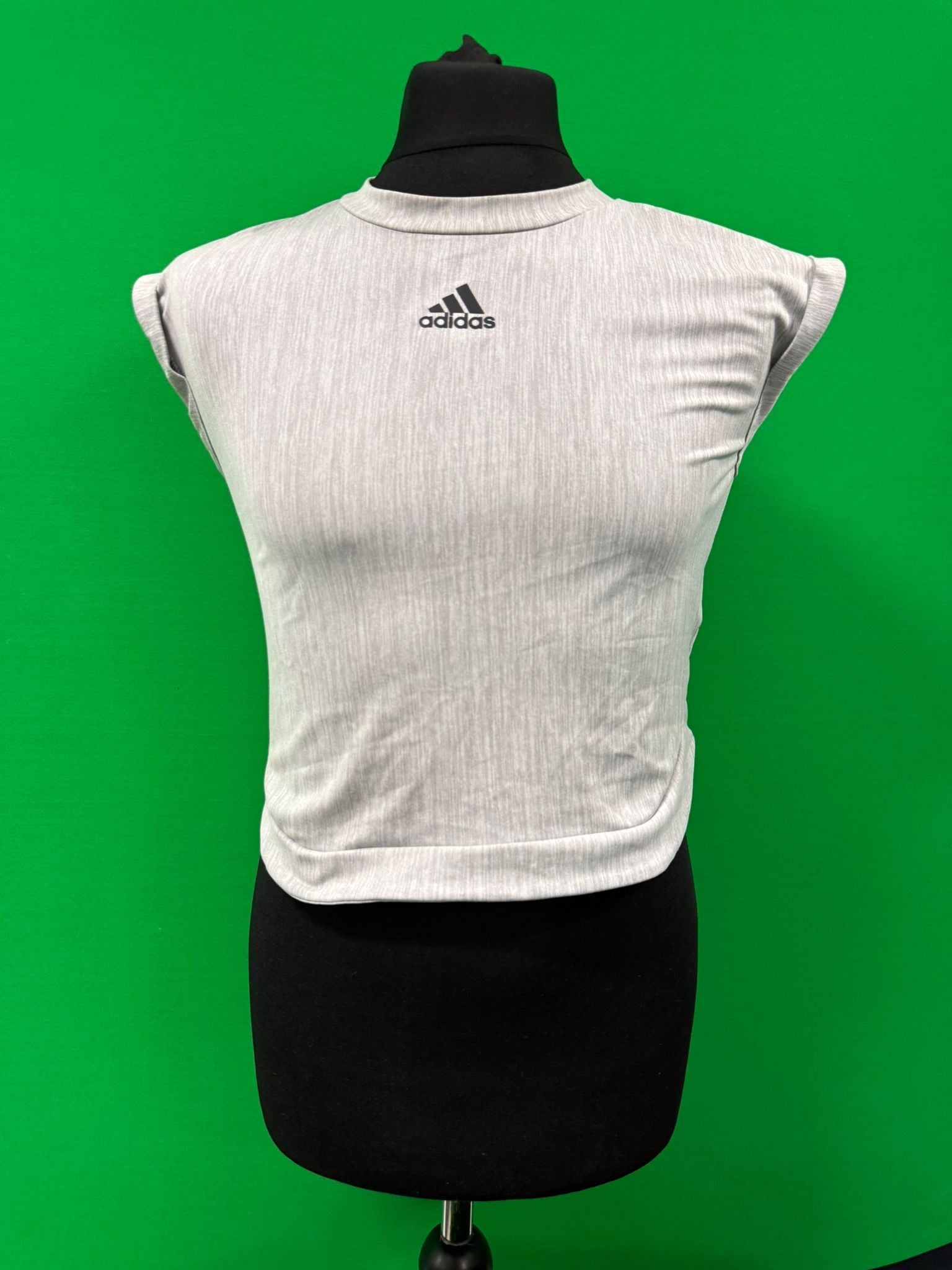 Front view of a light grey Adidas mesh training top for women displayed on a mannequin with a green background