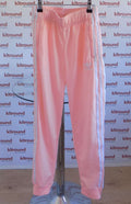 Front view of adidas peach tracksuit bottoms with white stripes