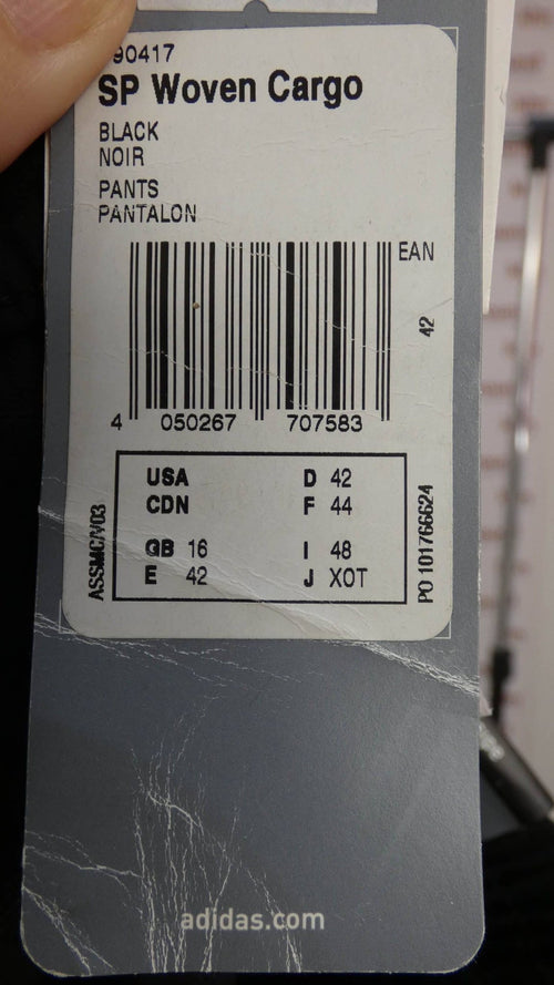 Close-up of Adidas woven cargo trousers swing tag showing size and barcode