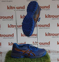 Pair of blue Asics hockey shoes with orange details, side and sole view shown on artificial grass