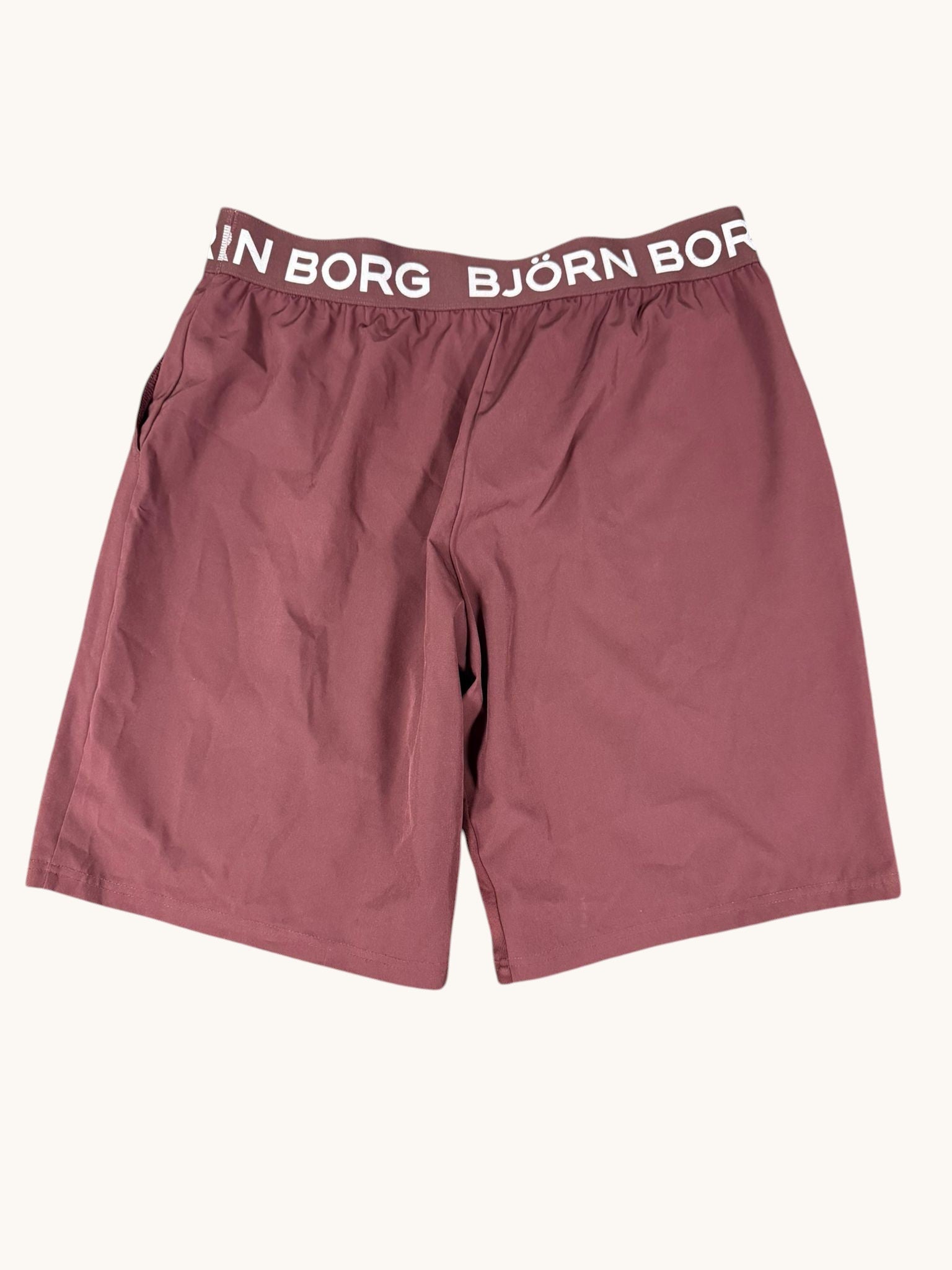 Björn Borg maroon training shorts with white logo waistband and drawstring. Lightweight poly-blend fabric with side pockets.