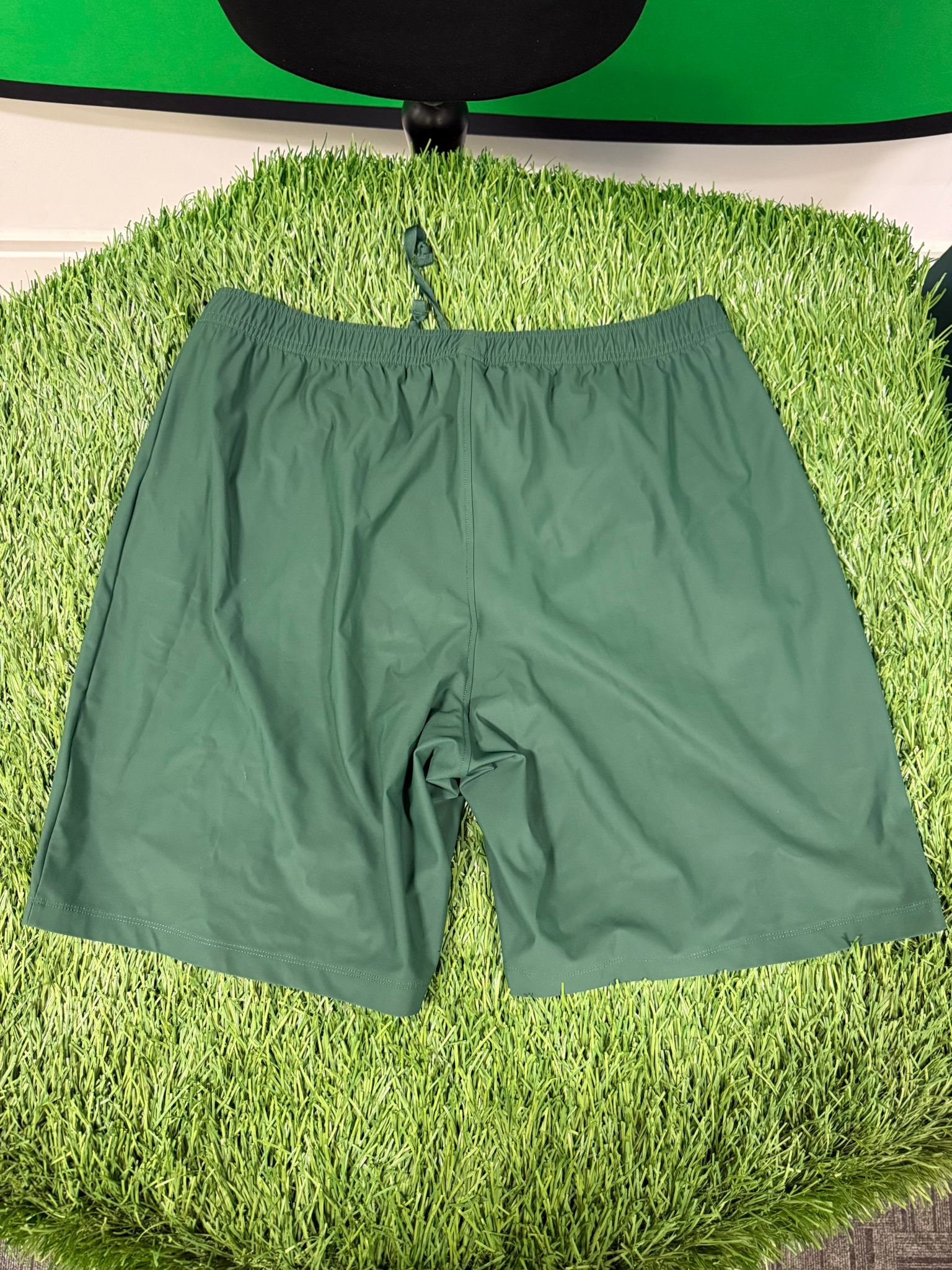 Back view of Bjorn Borg men's green tennis shorts on artificial grass