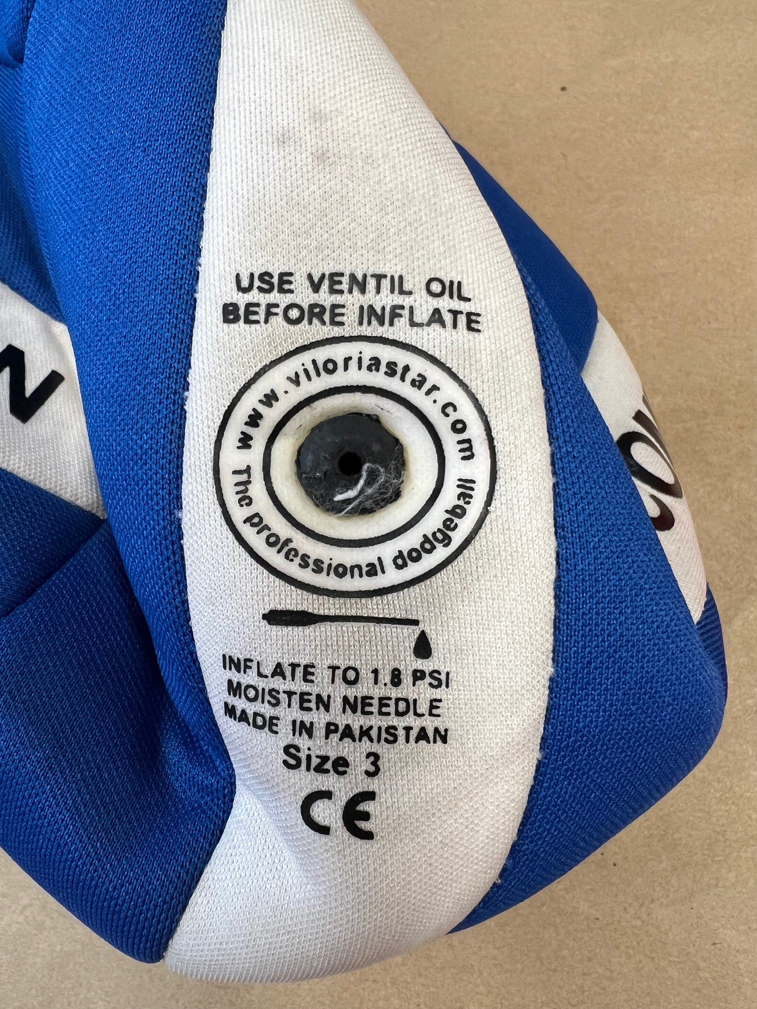 Close-up of inflation valve on blue and white size 3 dodgeball with instructions