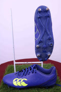 Blue Canterbury rugby boots displayed on artificial turf showing stud pattern