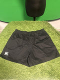 Black Canterbury rugby shorts with logo displayed on green surface