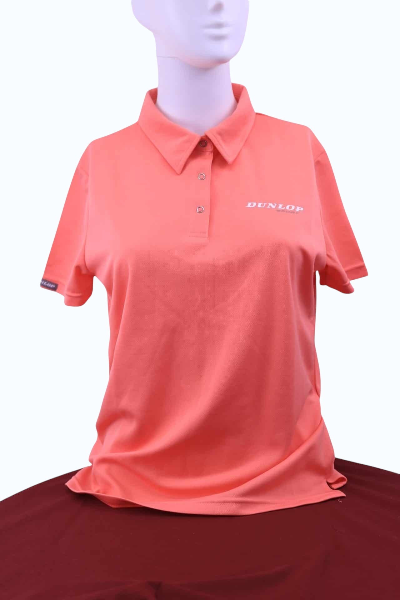 Women's Dunlop Sport polo shirt in melon orange with press stud buttons and a small logo on the chest.