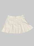 White pleated Fila tennis skirt laid flat on artificial grass