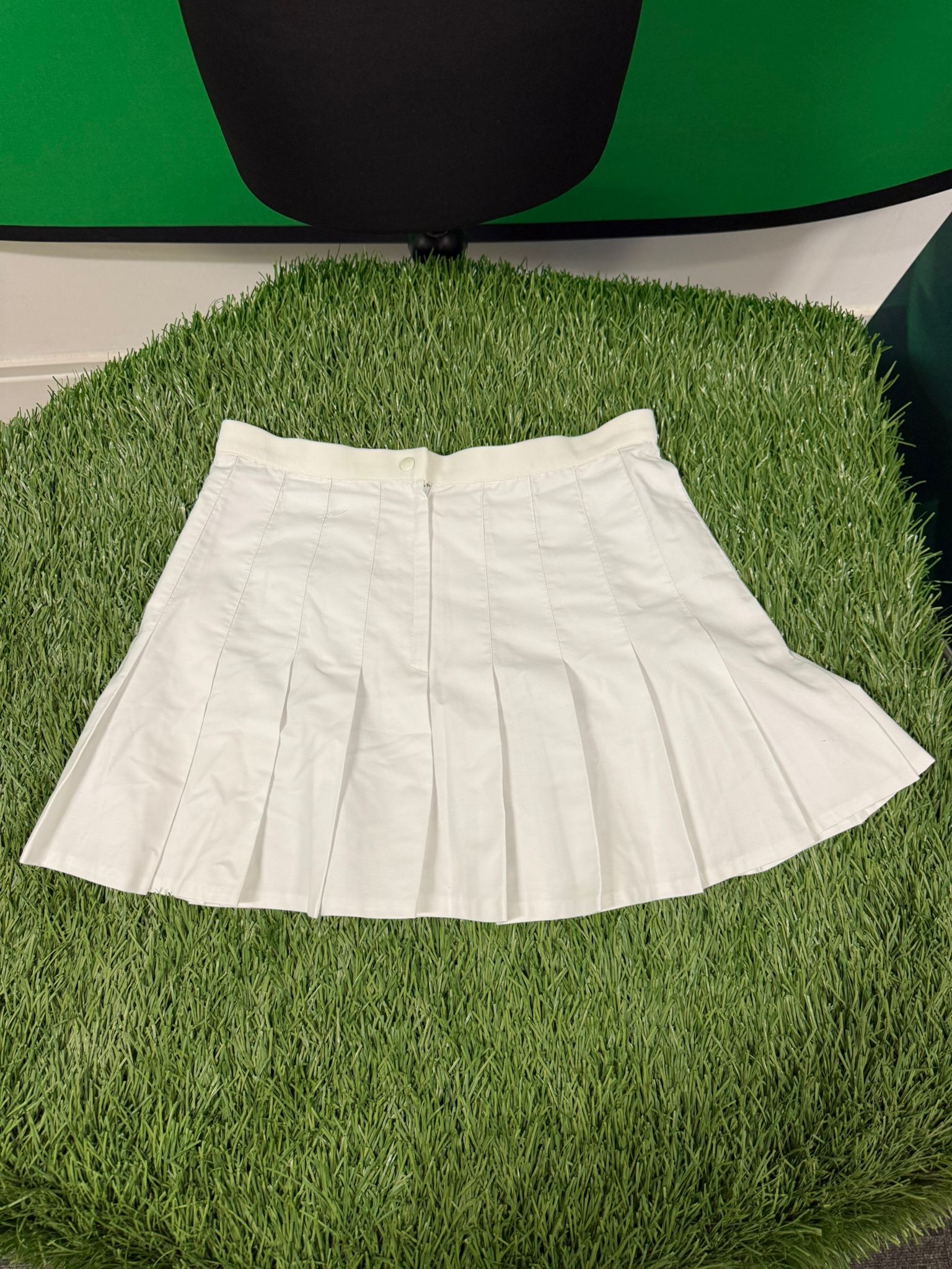 White pleated Fila tennis skirt laid flat on artificial grass