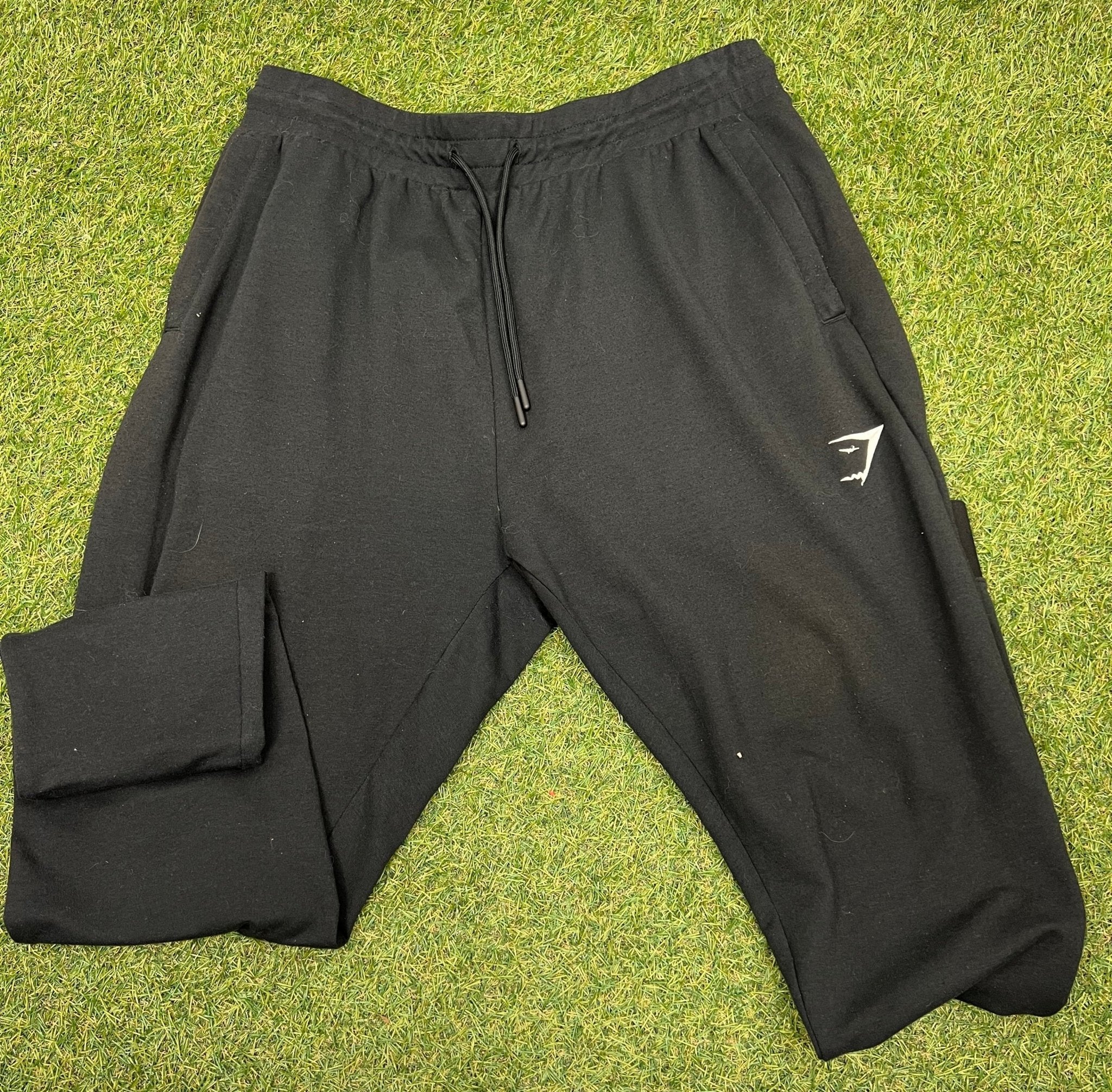 Front view of Gymshark black tracksuit bottoms size L on grass