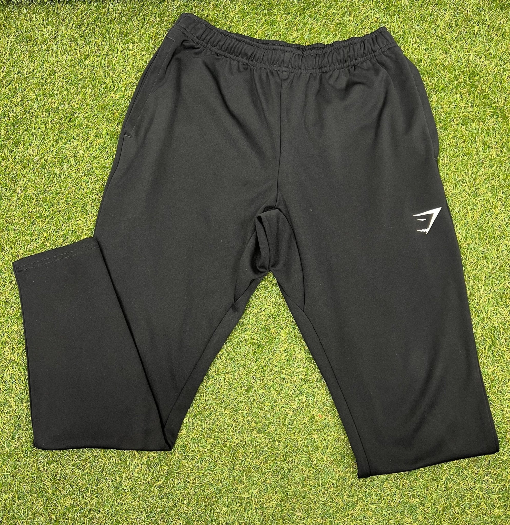 Front view of black Gymshark tracksuit bottoms on grass